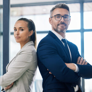 Partnership, arms crossed and teamwork with two business people standing together in corporate office building. Success, motivation and vision with employees in innovation or management company